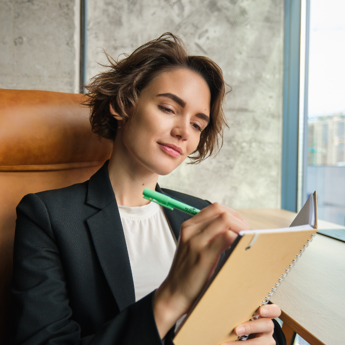A person in an office using a promotional pen and notebook.